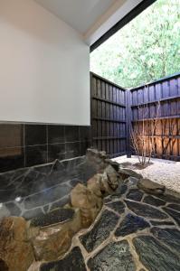 La salle de bains est pourvue d'une grande baignoire avec des rochers. dans l'établissement Hinata-an Botan - Vacation STAY 86855, à Yufu