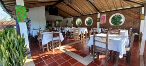 un restaurante con mesas y sillas blancas en una habitación en Finca Hotel Villa Del Sol, en Pueblo Tapado