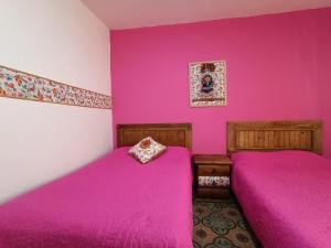 two beds in a room with pink walls at Posada Casa Mexicana Jamaica in Mexico City