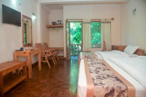 um quarto de hotel com duas camas, uma mesa e cadeiras em Chitwan Paradise Hotel em Sauraha