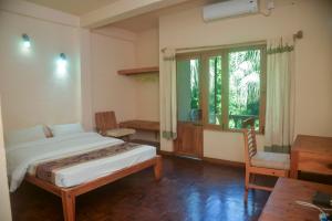 a bedroom with a bed and a desk and a window at Chitwan Paradise Hotel in Sauraha