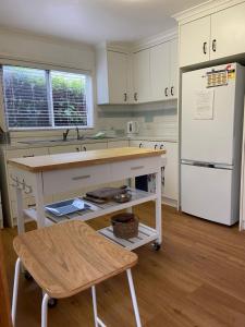 a kitchen with a table and a white refrigerator at Griffith St Beach House in Port Fairy