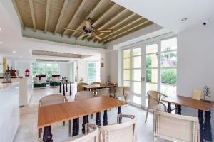 a dining room with a ceiling fan and tables and chairs at De Pastel Hua Hin in Hua Hin