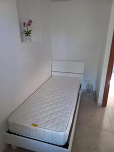 een wit bed in een kamer met een vaas met bloemen bij GREEN HOUSE in Vasto