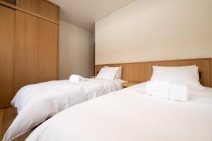 two beds in a room with white sheets at Shion in Kutchan