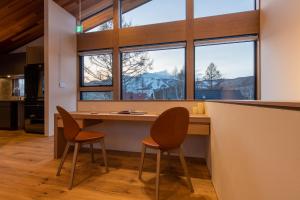 a kitchen with two chairs and a table with windows at Shion in Kutchan