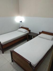 テガルにあるHOTEL MAYAのベッド2台、テーブル(ランプ付)が備わる客室です。