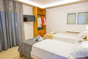 a hotel room with two beds and a tv at Rhodes City Center Suite in Rhodes Town