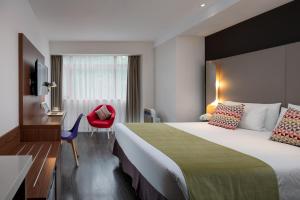 una camera d'albergo con un grande letto e una sedia rossa di Campanile Xi'an Bell Tower Huimin Street a Xi'an