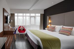 ein Hotelzimmer mit einem großen Bett und einem roten Stuhl in der Unterkunft Campanile Xi'an Bell Tower Huimin Street in Xi'an
