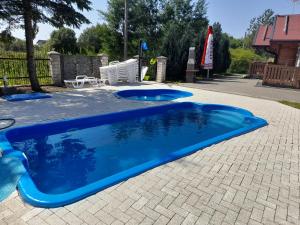 a blue swimming pool with two chairs and a table at Onyx in Mielno