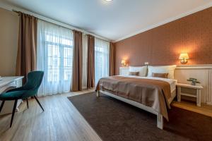 Cette chambre comprend un grand lit et un bureau. dans l'établissement Wellness Hotel Pivovar Monopol, à Teplice