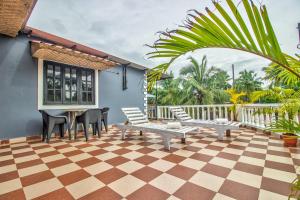 - une terrasse avec des chaises et une table sur un sol en damier dans l'établissement Villa Verediana, à Candolim
