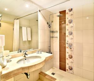 a bathroom with a sink, mirror, and bathtub at Hotel Sandy Beach in Albena