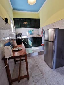 a kitchen with a stainless steel refrigerator and a table at Pelekas Beach Apartments in Pelekas