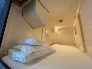 a bed with white sheets and pillows in a room at カプセル&サウナ日本 -男性専用 men only- in Fukuyama
