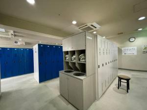 a large room with blue lockers and a stool at カプセル&サウナ日本 -男性専用 men only- in Fukuyama