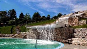 a waterfall in a pool with a stone wall at A First class za 4 osobe 2 spavaće sobe in Tuzla
