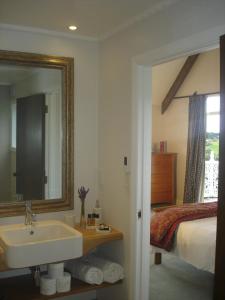 a bathroom with a sink and a bed and a mirror at Country Homestead at Black Sheep Farm in Waipu