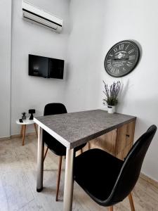 a table with two chairs and a clock on a wall at Central Double Room Ground floor in Heraklio Town