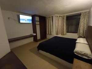 a bedroom with a bed and a flat screen tv at El Arrayan in Valle de Bravo