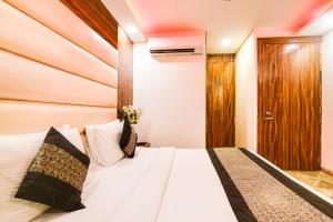 a bedroom with a white bed with a wooden headboard at Hotel Olivia Inn At Delhi Airport in New Delhi