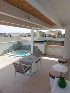 a rooftop patio with a table and a swimming pool at MandorleOlio in Polignano a Mare