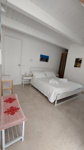 a white bedroom with a large bed and a chair at MandorleOlio in Polignano a Mare