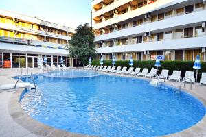a swimming pool in a hotel with chairs and umbrellas at Hotel Oasis in Albena