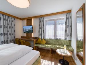 フューゲンにあるHotel Landhaus Zillertalのベッドとデスクが備わるホテルルームです。