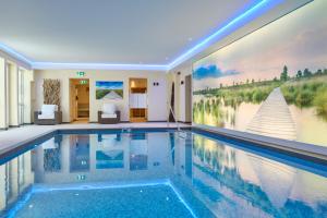 a swimming pool in a house with a painting on the wall at Landhotel Kallbach - 4 Sterne SUPERIOR in Hürtgenwald