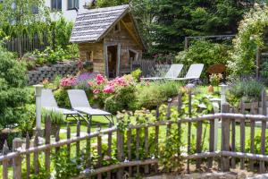 a garden with chairs and a stone house at Hotel Landhaus Zillertal in Fügen