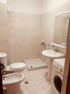 a bathroom with a toilet and a sink and a washing machine at Balkan Apartaments in Shëngjin
