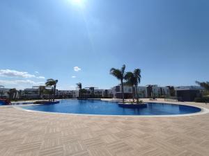 une grande piscine avec des palmiers et des bâtiments dans l'établissement Your Four Seasons, à Boghaz