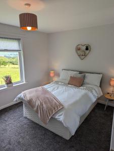 een slaapkamer met een groot bed en een raam bij Rural Cosy Three Bedroom Cottage in Girvan
