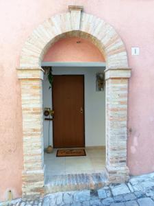 um arco que conduz a uma porta num edifício cor-de-rosa em La Casa di LEO - Apartments em Recanati