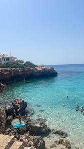 a group of people playing in the water at a beach at Beach house Cala Morlanda in S'Illot