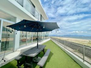 福岡的住宿－Luxury Villa Saitozaki UMIHOTARU，房屋阳台上的带遮阳伞的长凳