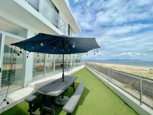 eine Bank mit einem Regenschirm auf dem Balkon eines Hauses in der Unterkunft Luxury Villa Saitozaki UMIHOTARU in Fukuoka