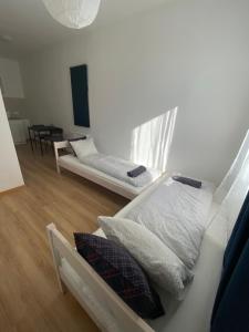 two beds in a room with wooden floors at Budapest Airport-Vecsés Trainstation Apartman K7 in Vecsés