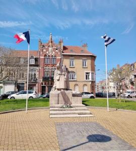 a statue in front of a building with two flags at Appartement Malo les Bains à deux pas de la plage in Dunkerque