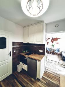 kuchnia z białymi szafkami i żyrandolem w obiekcie Apartamencik Nad Jeziorem Dzwon Marcinkowo 51 - 2 w mieście Mrągowo