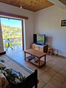 a living room with a couch and a tv and a table at Arsos Village Apartment in Arsos