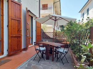 a wooden table and chairs with an umbrella on a patio at APPARTAMENTO CALETTA 2 in Castiglioncello