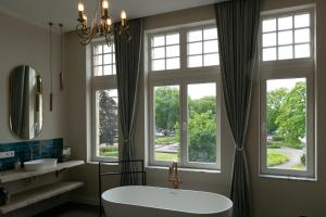 a bathroom with a tub and two windows at Fantastisch Herenhuis ENSEMBLE in Ypres +38 photos