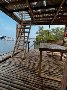 a wooden deck with a bench and a ladder at Onyong's Floating Cottage in Calatagan