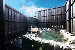una bañera de hidromasaje en un patio trasero con una valla de madera en Yufuin Yukari-an Megumi no Sato en Yufuin