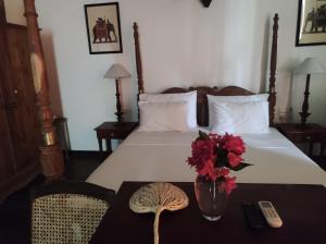 a bedroom with a bed and a table with flowers on it at Villa seven faces in Galle