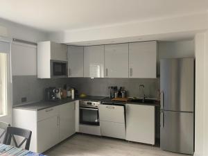 a kitchen with white cabinets and a stainless steel refrigerator at Hus på bakken in Skaland