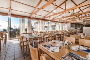 a restaurant with wooden tables and chairs and windows at Hotel Europalace in Playa del Ingles